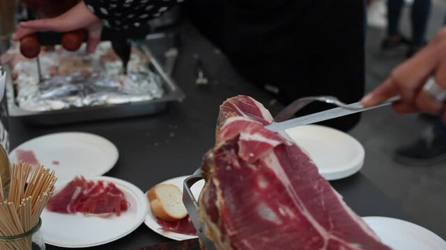 Woman cutting Italian ham, called prosciutto with a ham knife.
