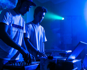 Disc jockeys or DJ stands behind the sound mixing console, makes sound at the party