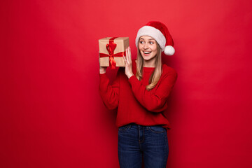 Christmas woman holding christmas gifts smiling. Cute beautiful Caucasian santa woman isolated on red background