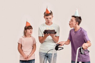 Teenaged disabled boy blowing out candles on cake while celebrating his birthday together with...