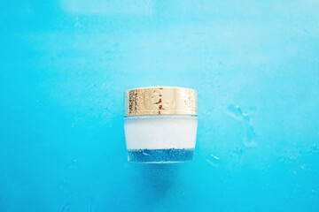 Cosmetic cream jar on blue background with water drops.
Moisturizing cream concept. Copy space
