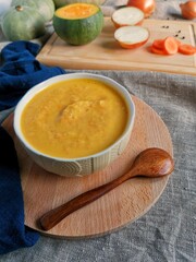 Vegetarian autumn pumpkin cream soup on burlap background with sliced vegetables