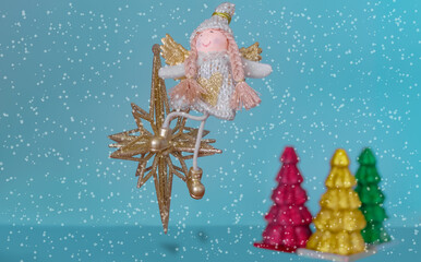 Photo-card of New Year decorations star, girl angel, decorative Christmas trees on a blue background and snowflakes