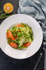 salad with slices of fresh salmon in a white plate on a dark background. Seafood salad