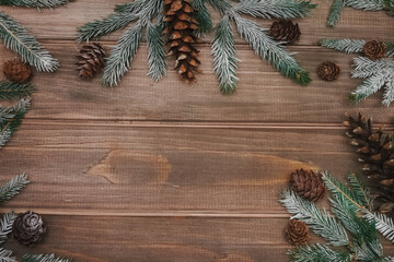 textured brown wooden background with spruce branches with cones in snow