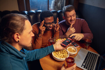 Having fun. Excited fans in bar with beer and mobile app for betting, score on their devices. Screen with match results, emotional friends cheering. Gambling, sport, finance, modern techn concept.