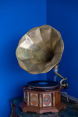 Vintage gramophone. Old record players take on the blue background. Golden gramophone with disk on wooden box isolated on blue background. 