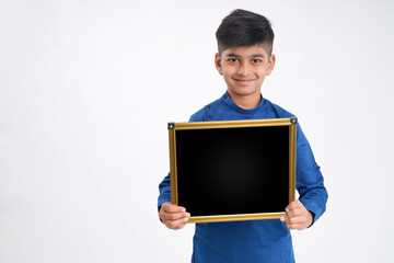 Cute indian little boy showing black board with copy space over white background