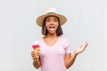 young hispanic woman feeling happy, excited, surprised or shocked, smiling and astonished at...