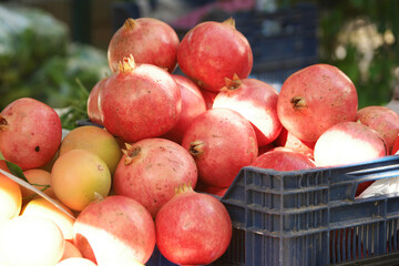 Pomegranates in box at market stall. Organic fruits on sale at street market. Healthy eco food.