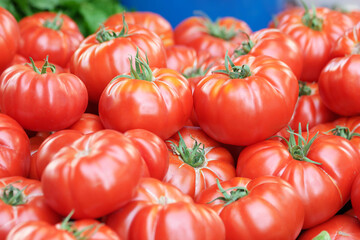 Many red ripe tomatoes close up. Organic tomatoes on market stall. Local vegetable shop.