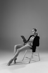 Fototapeta premium Contracts. Young fashionable, stylish woman wearing jacket and socks working from home. Fashion during insulation 'cause of coronavirus pandemic. Half business and half home style. Black and white.
