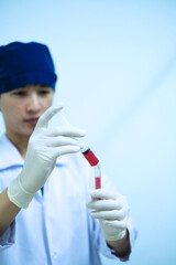 medical technician dropping blood sample to test tube in hospital laboratory