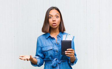 young hispanic woman feeling extremely shocked and surprised, anxious and panicking, with a...