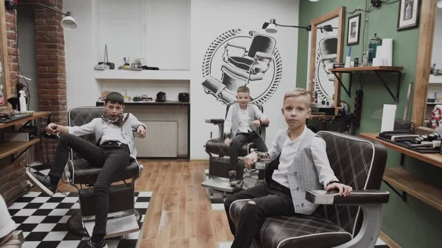 The barber is cutting hair and designing hairstyles for little  boy