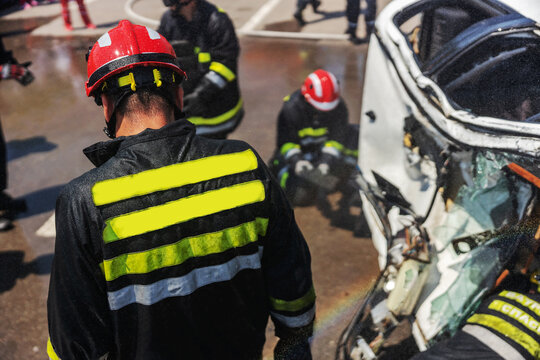 Firemen trying to release man from crashed car. There is a crashed cars in car accident.
