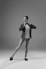 Posing. Young fashionable, stylish woman wearing jacket and socks working from home. Fashion during insulation 'cause of coronavirus pandemic. Half business and half home style. Black and white.