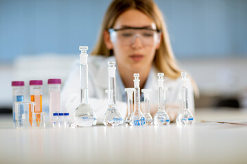 Fototapeta premium Female medical or scientific researcher looking at a flasks with solutions in a laboratory