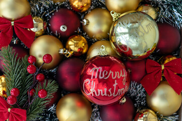 Gold and red Christmas balls with red bows. Big red Christmas ball with words Merry Christmas. Christmas background. New Year or Xmas concept. Top view.