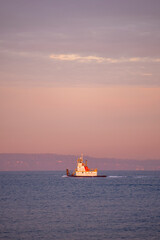 A tugboat in Seattle moving west through Puget Sound at sunrise