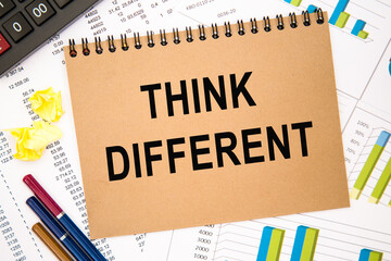 Text THINK DIFFERENT on notepad with office tools, pen on financial report . Business and financial conzept. calculator and the working paper with a diagram.