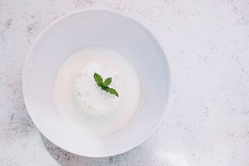 Fromage blanc de brebis frais et petit lait avec une feuille de menthe dans un bol blanc