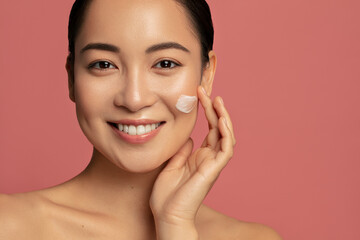 Hydration and skin care concept. Young beautiful asian model posing with applayed cream on her face