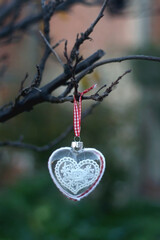 Heart shaped Christmas ornament, hanging in the garden. Selective focus.