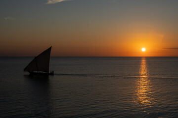 Wooden sailboat on the clear water of Zanzibar island during sunset..