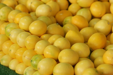 Fresh organic yellow lemons on pile at market. Raw citus fruits texture. Healthy food industry.