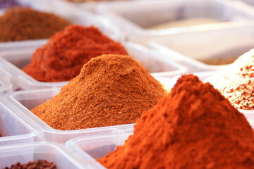 Containers with assorted oriental spices. Various powder seasonings in platic boxes. Turkish spices store. Traditional oriental cuisine.