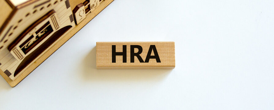 House Rent Allowance symbol. Wooden block with word 'HRA, House Rent Allowance' near miniature house. Beautiful white background, copy space. Business and HRA concept.