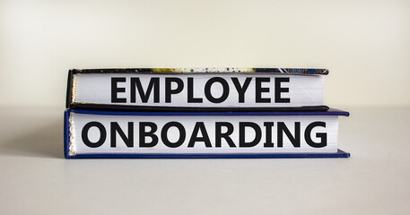 Employee onboarding symbol. Books with text 'employee onboarding' on beautiful white table. White...