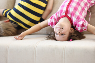 Funny child stand upside down on sofa and play. children activity in nursery.