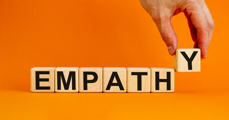 Empathy symbol. Concept word 'empathy' on wooden cubes on a beautiful orange background. Male hand. Psychological and empathy concept, copy space. - obrazy, fototapety, plakaty