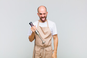 young bald man with cheerful, carefree, rebellious attitude, joking and sticking tongue out, having...