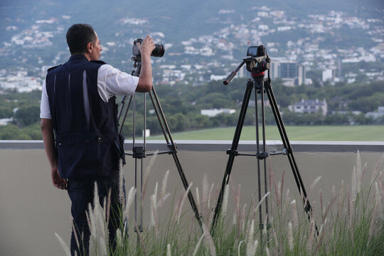 camar&oacute;grafo tomando foto y video con dos c&aacute;maras con paisaje de cerro al fondo
