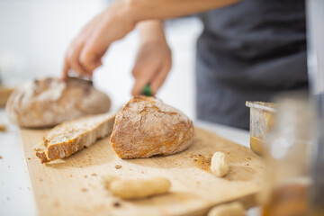 Female hands slicing bread on a cutting board