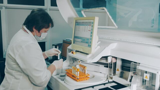 Microbiologist conducts research in the laboratory. The researcher performs a biochemical analysis test. A female laboratory worker works with a biochemical analysis device.