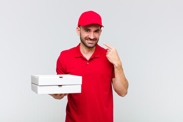 young bald man smiling confidently pointing to own broad smile, positive, relaxed, satisfied...