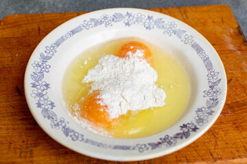 Flour with raw chicken eggs in a plate. Chop batter, frying.