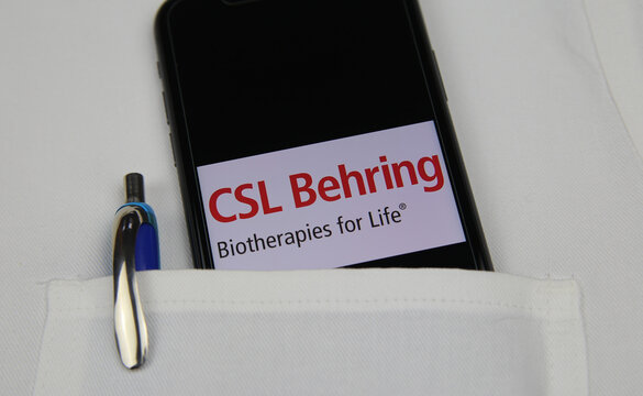 Viersen, Germany - April 9. 2020: Close up of mobile phone screen with logo lettering of CSL Behring pharmaceutical company in pocket of white doctors coat with pencil