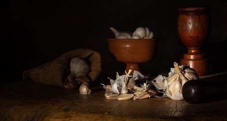 Garlic, arrangement with garlic heads and accessories on rustic wooden surface, abstract background, low key image, selective focus.