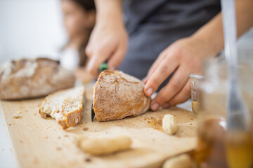 Female hands slicing bread on a cutting board