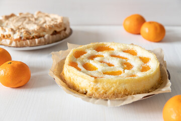 amerikanischer Cheesecake oder Käsekuchen mit  orangen Mandarinen zur Weihnachtszeit im Winter auf einem Tisch aus Holz