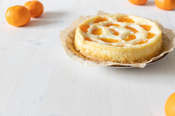 amerikanischer Cheesecake oder Käsekuchen mit  orangen Mandarinen zur Weihnachtszeit im Winter auf einem Tisch aus Holz