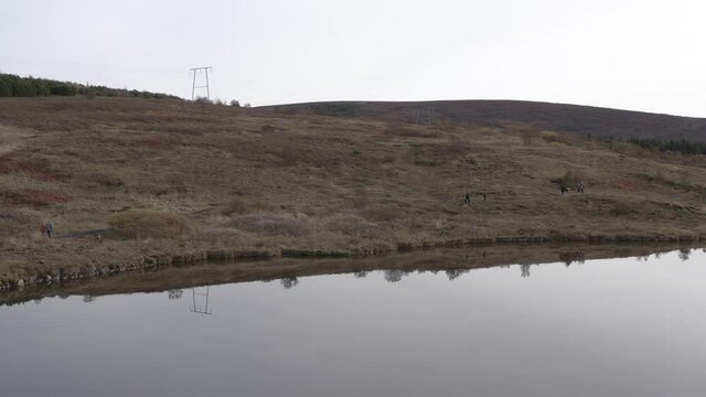 Aerial of lake V&iacute;filssta&eth;avatn with flat water and people walking on shore