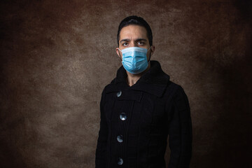 Portrait of a man. The guy in the medical mask. Portrait on a brown background. health protection