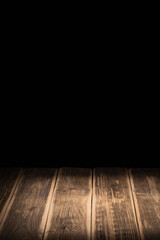 A ray of light on a wooden table against the background of a black wall for chalk, spruce branches