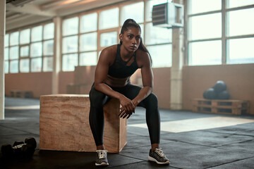 Serious ethnic female athlete resting near dumbbells - Powered by Adobe